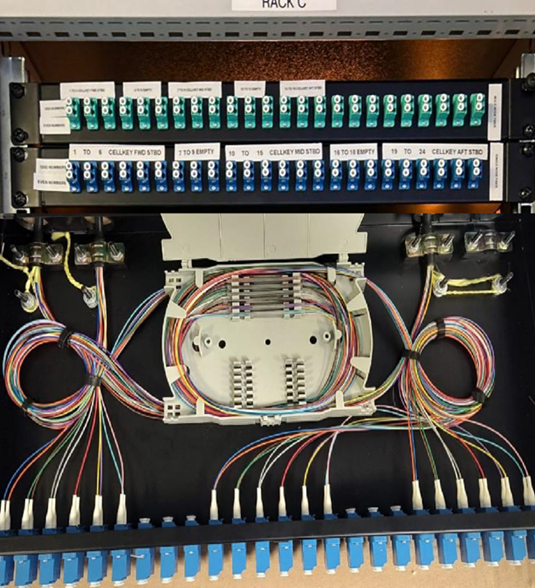 Fiber optic ODF patch panel with organized patch cords and splice tray for marine communication networks.